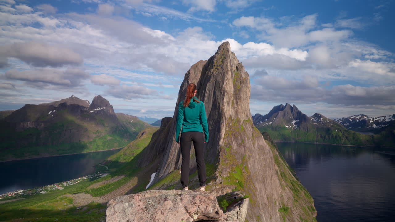 Heroic rear view of female hiker looking out at scenic Segla mountain, Fjordgard