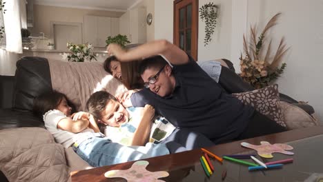 mother tickling her children on the sofa at home