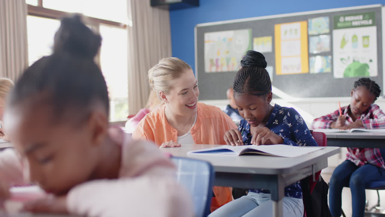 In school, female teacher helping student with writing assignment in classroom