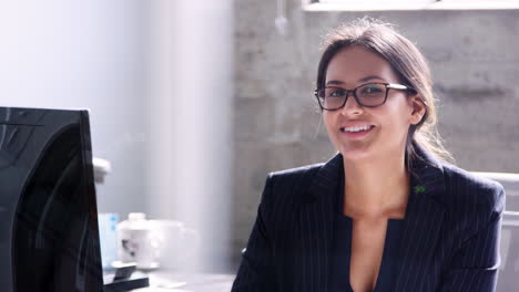 Young-businesswoman-working-in-her-office,-smiles-to-camera