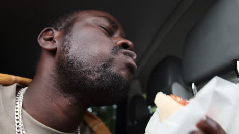 Man-enjoying-hot-dog-in-van