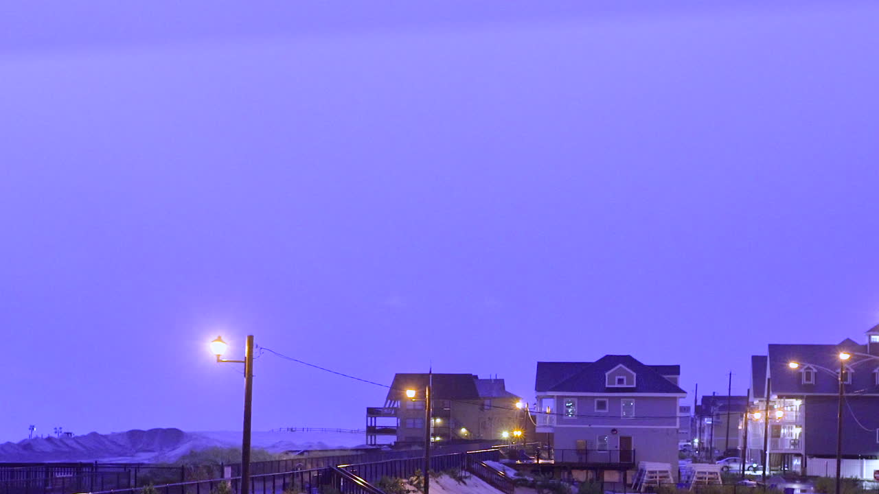 해변의 잔잔한 주차장 위 하늘을 가로질러 서사시적인 번개 사슬을 만드는 큰 폭풍