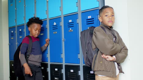 in school, african american boy pointing at classmate near lockers, looking upset
