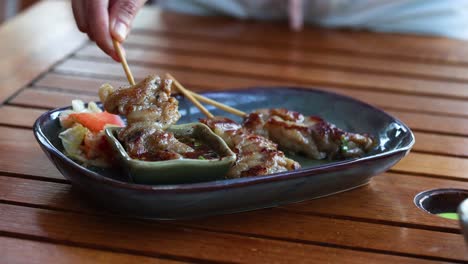 hand picking up grilled skewers from a dish