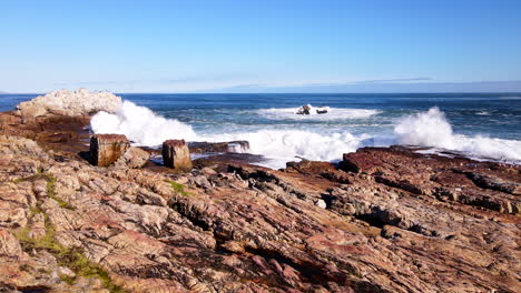 Tumultuous-ocean-waves-thrash-jagged-rocky-shoreline-of-Hermanus