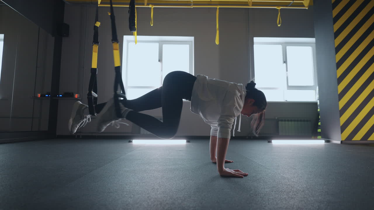 fitness TRX training exercises at gym woman push-up workout. Attractive woman doing exercise for hands in gym. core abs crossfit oblique training with fitness straps in the gym's studio.