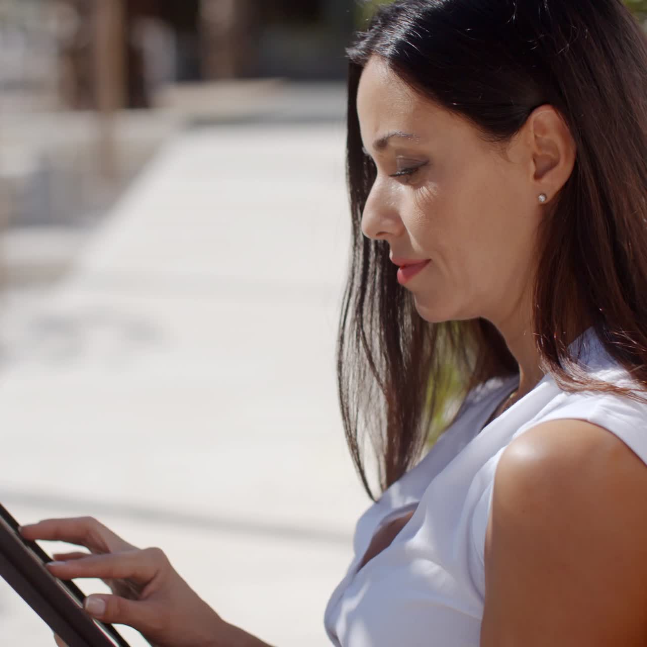 mujer joven sonriente que usa su tableta al aire libre