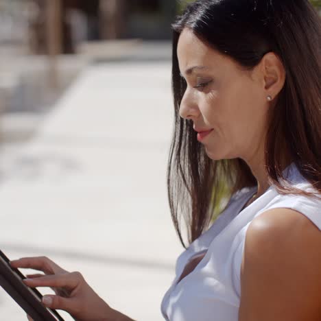 smiling young woman using her tablet outdoors