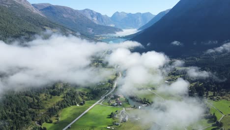 flying over valley with glacier lake down there, mist and high mountains o