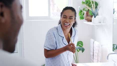 Couple-Wearing-Pyjamas-Standing-In-Bathroom-At-Sink-Brushing-Teeth-In-The-Morning