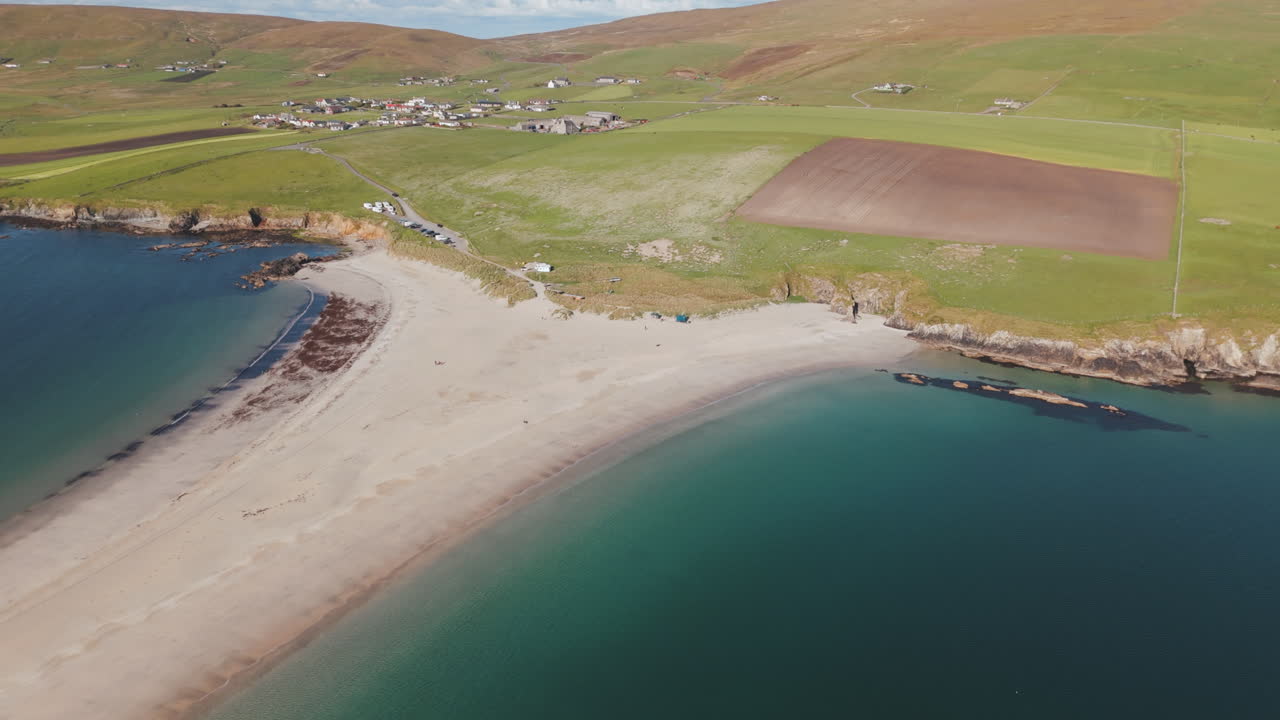 An aerial shot of beautiful St Ninian’s beach, in Bigton Shetland on a warm, calm summers day in Northern Scotland.