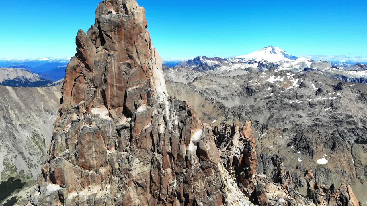 Ascending drone view of sharp granite peak Torre Principal, revealing Cerro Tronador in distance and clear sky, Frey, Bariloche, Argentina.