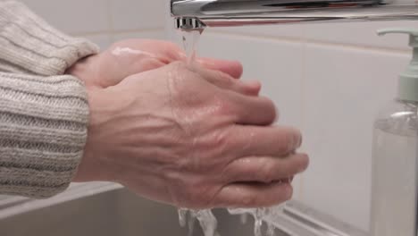 hombre lavándose las manos con jabón líquido en el baño