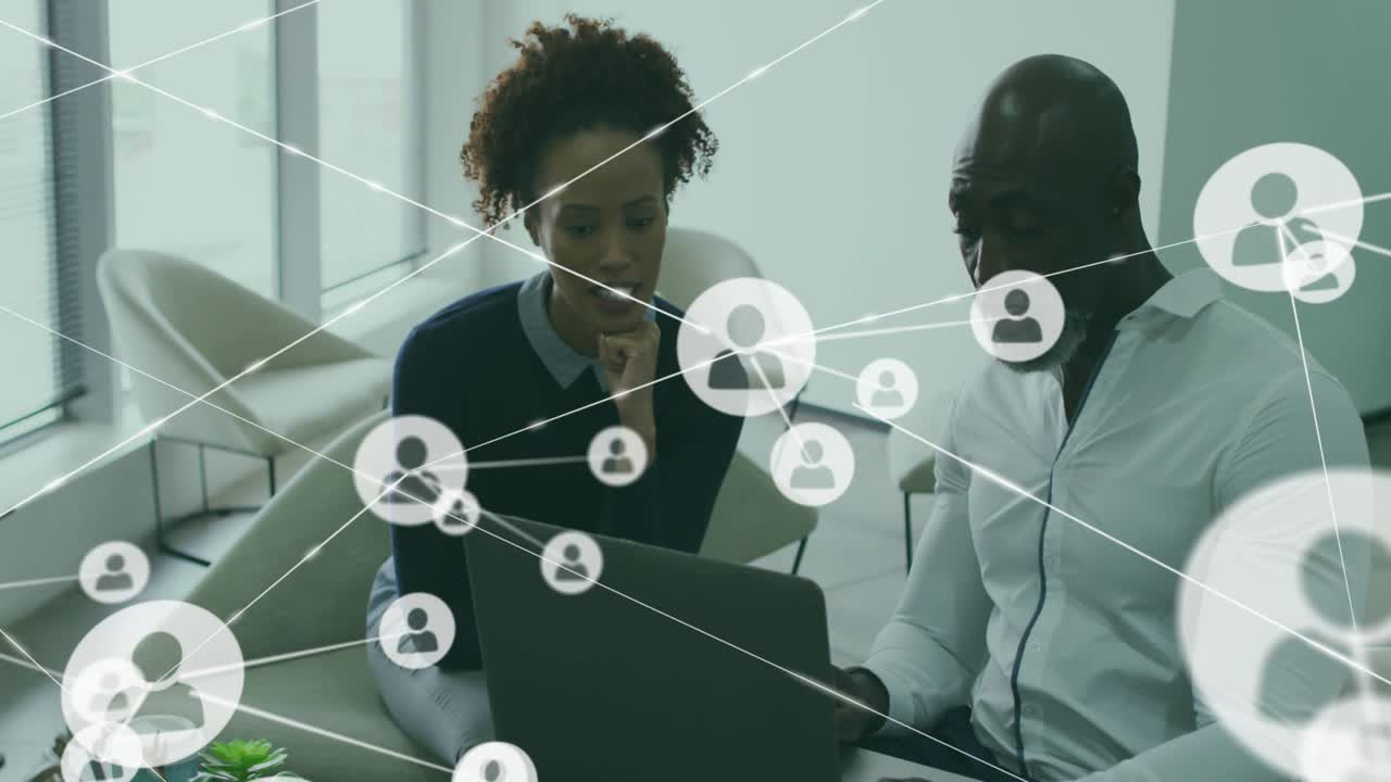 Mature man shifting laptop while woman leaning, network overlay expanding from screen for business