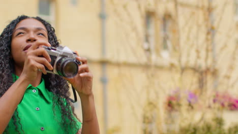 turista femenina con cámara de vacaciones en oxford, reino unido explorando la ciudad caminando por broad street tomando fotos 3