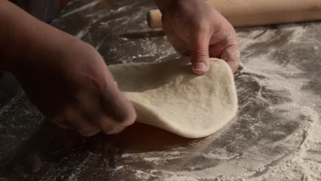 Rolling-and-kneading-dough-for-flatbread-baking,-closeup-on-hands