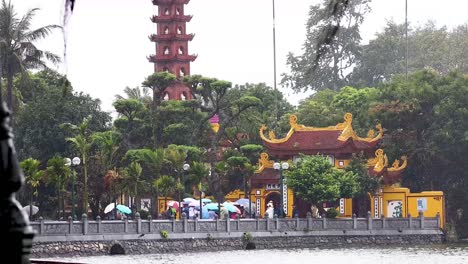 visitors with umbrellas at tran quoc pagoda