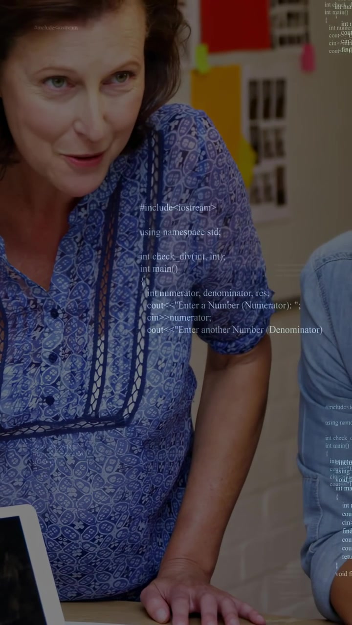 Vertical video: Mentor leaning forward pointing at laptop teaching colleague code overlaying frame