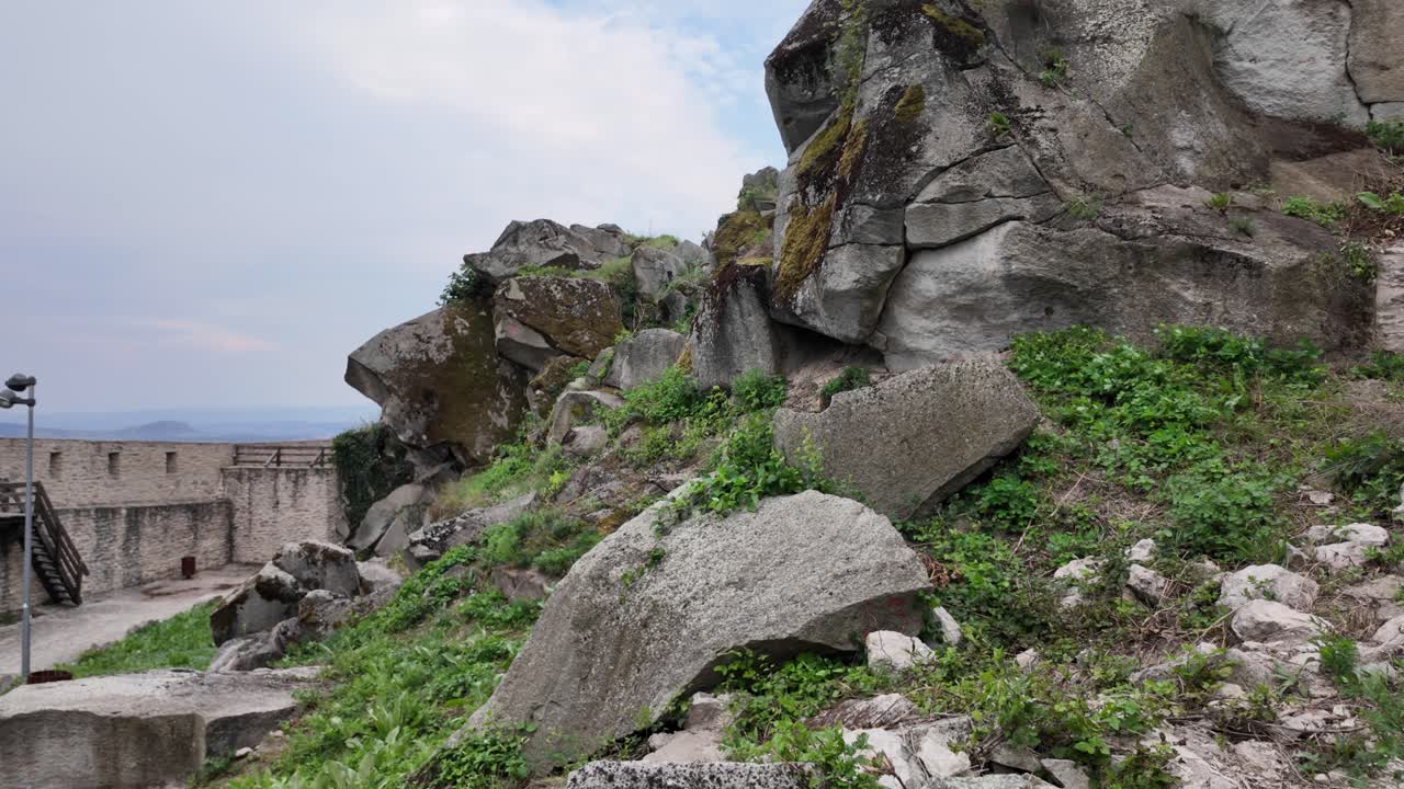 View of the interior of the Fortress of Deva, featuring ancient boulders, crumbling stone structures, and a sense of medieval history