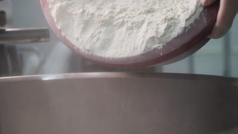 chef adding flour to mixing bowl