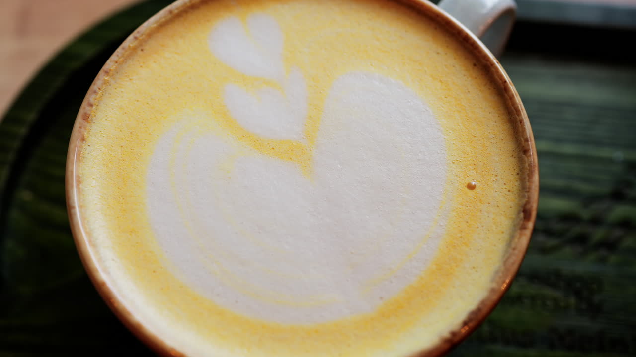 Close up of a heart-shaped latte art in golden turmeric coffee