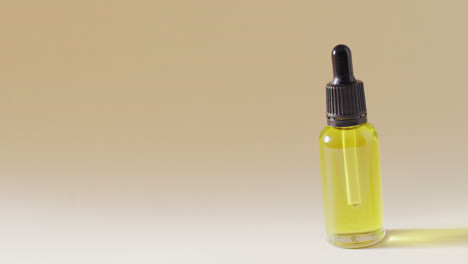 close up of dropper serum bottle on beige background with copy space