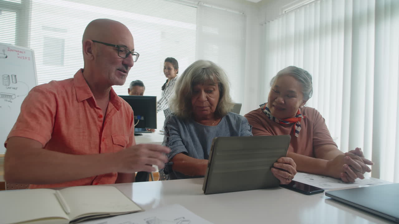 Aged Woman Explaining to Students Tablet Features