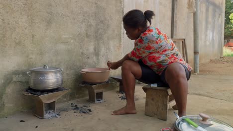 black female chef woman preparing a traditional ghanese food in a rustic rural outdoor kitchen in a village of ghana