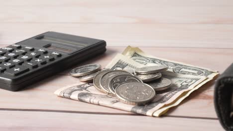 calculator, money, and coins on a wooden table