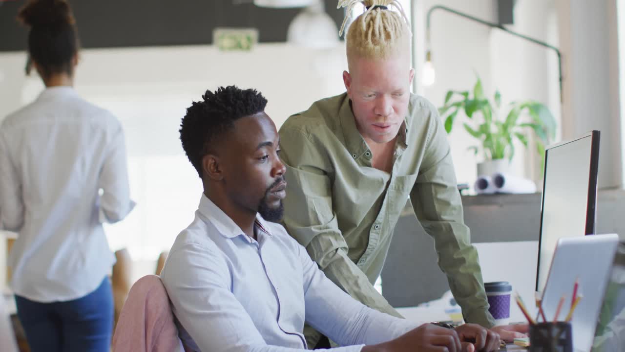 Diverse business people discussing with laptop in creative office