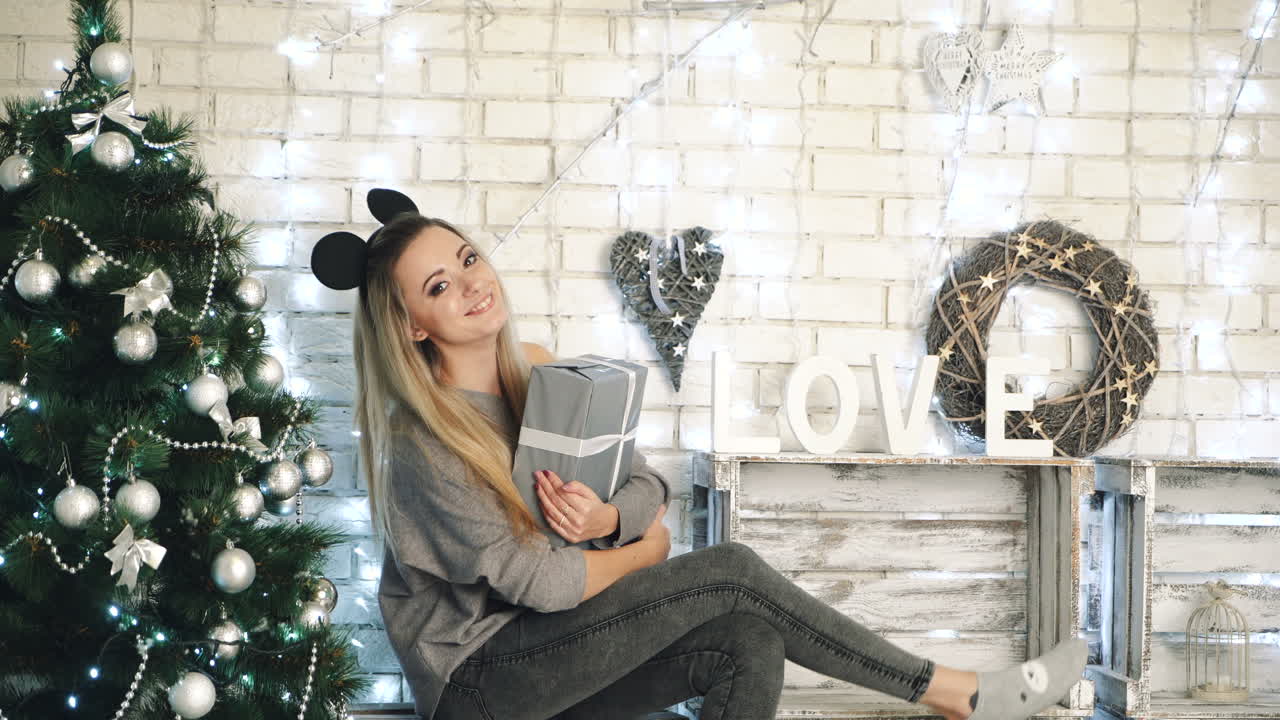 Woman with gift by Christmas tree