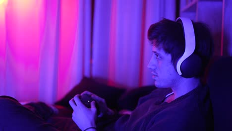 a concentrated man playing video games smiling with headphones looking at the tv screen