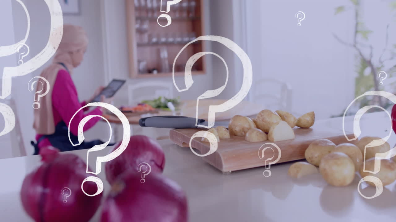 히자브를 입은 두 인종의 여성이 부에서 태블릿을 사용하고, 질문표를 넘습니다.