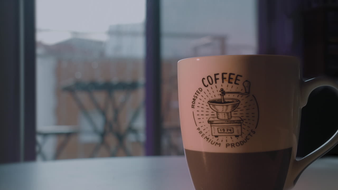 Tazza di caffè caldo fumante accanto alla finestra in una giornata piovosa