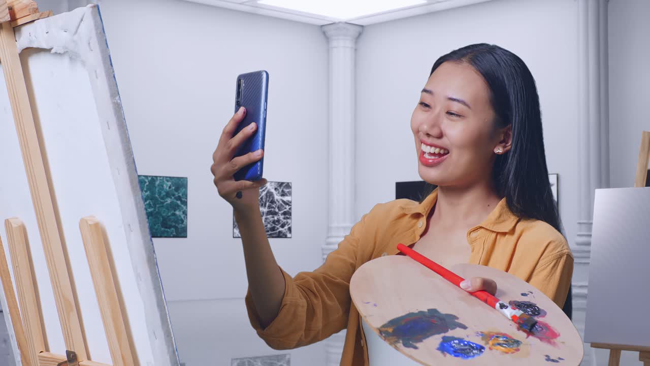 예술 스튜디오에서 그림을 그리는 동안 셀피를 찍는 여자