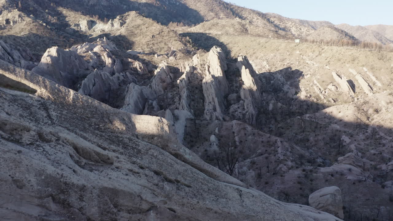 Drone footage of unique rock formations in a dry, mountainous landscape