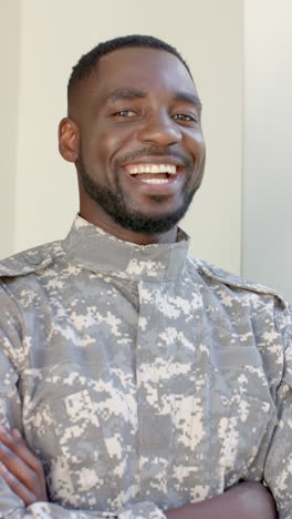 vertical video: smiling male soldier in uniform standing with arms crossed indoors