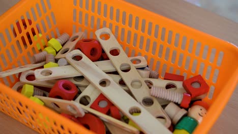 wooden construction toys in an orange basket