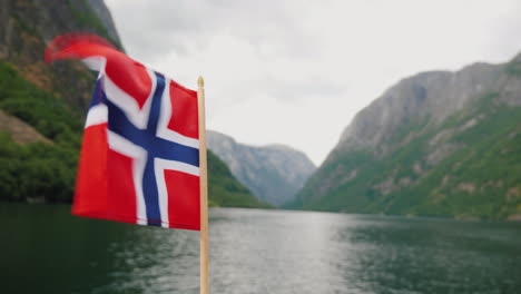 the norwegian flag flies in the wind against the backdrop of a majestic fjord cruise on the fjords o