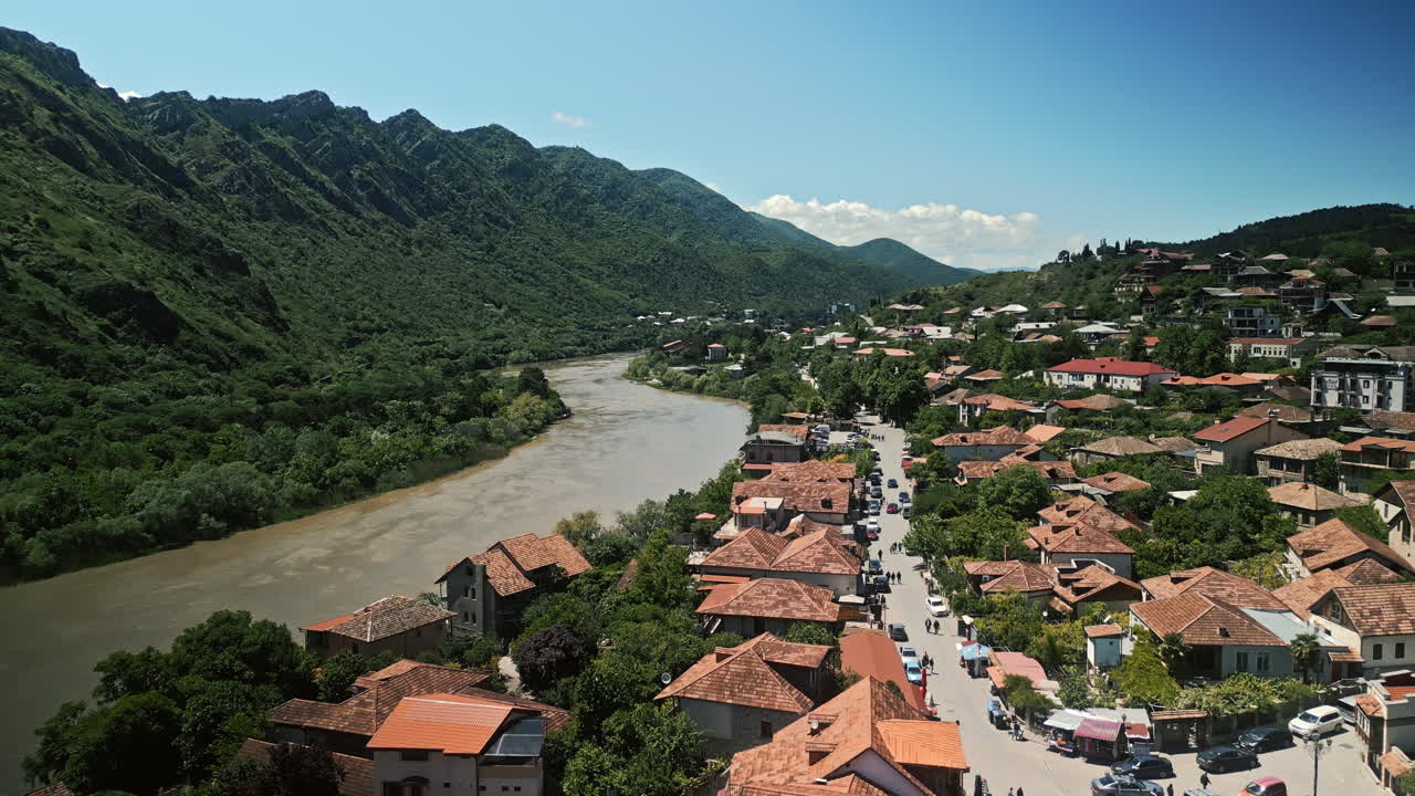 Panoramic View of a Riverside Town Nestled Among Green Mountains