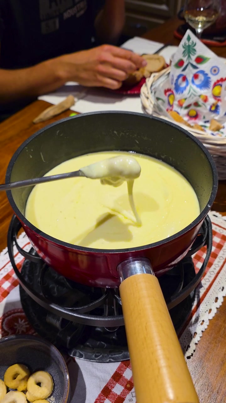 Gros plan vertical sur une fondue au fromage suisse traditionnelle dans un caquelon, avec le fromage en fusion. Dîner, cuisine suisse, plat réconfortant