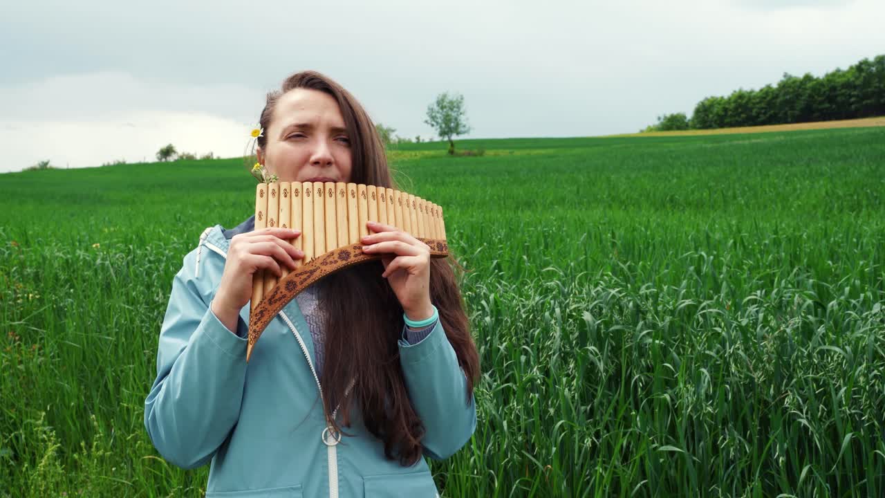 молодая женщина играет на панфлейте на природе