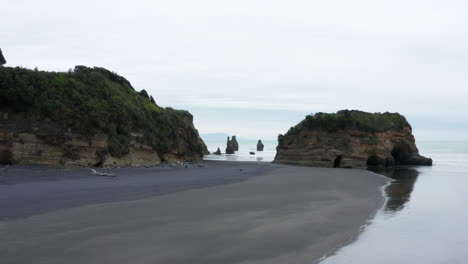 Drone-Flying-Towards-The-Three-Sisters-Beach-And-Elephant-Rock-Formation-In-Tongaporutu,-New-Zealand---Tourist-Attraction---low-aerial