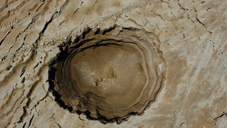 7 meter deep sinkhole on the shores of the dead sea created by the dissolution of the salt in the ground due to the lowering of seawater - the area is dangerous and closed to entry