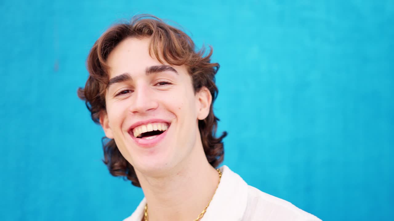 Caucasian young man smiling at camera in a blue background