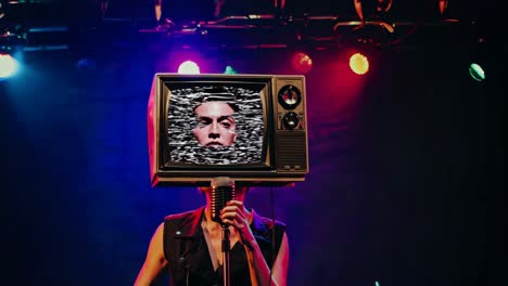 persona con cabeza de tv cantando en el escenario
