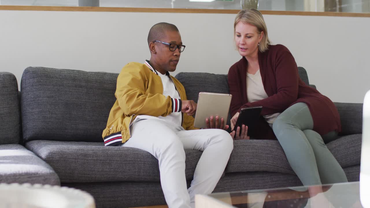 diversos colegas masculinos y femeninos sentados en el sofá, hablando de negocios en la oficina