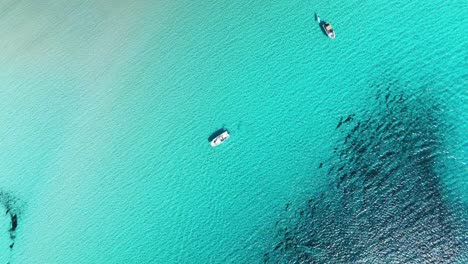 yachts floating off the island of menorca in spain with shallow bommie reefs next to the anchor