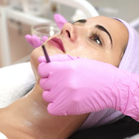 beautician applying peeling on woman's face in spa. face cosmetic procedure. concept of skin care