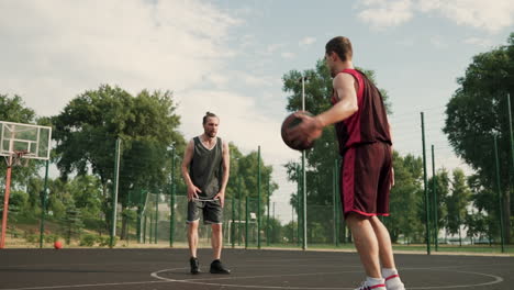 un hábil jugador de baloncesto regateando el balón entre las piernas contra su defensor contrario y lanzando el balón al aro de baloncesto al aire libre 1